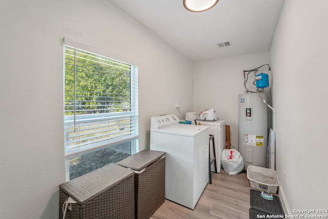 laundry room featuring light wood-type flooring, washer and clothes dryer, and electric water heater