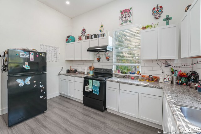 kitchen with white cabinets, light stone countertops, tasteful backsplash, black appliances, and light wood-type flooring