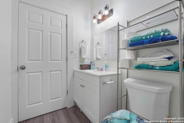 bathroom with hardwood / wood-style flooring, vanity, and toilet