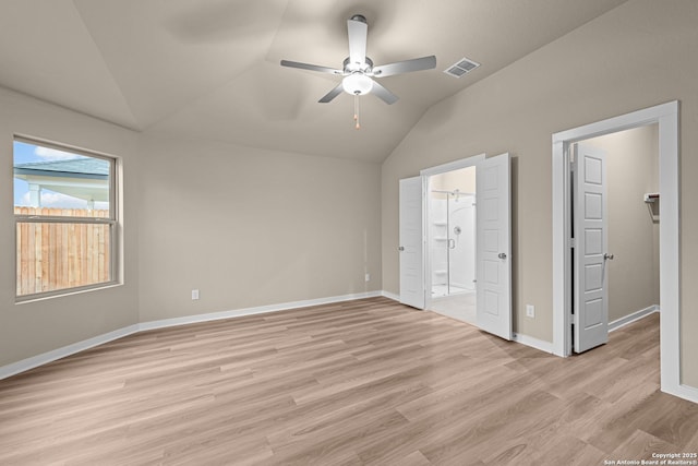 unfurnished bedroom with lofted ceiling, ensuite bath, light hardwood / wood-style flooring, ceiling fan, and a spacious closet