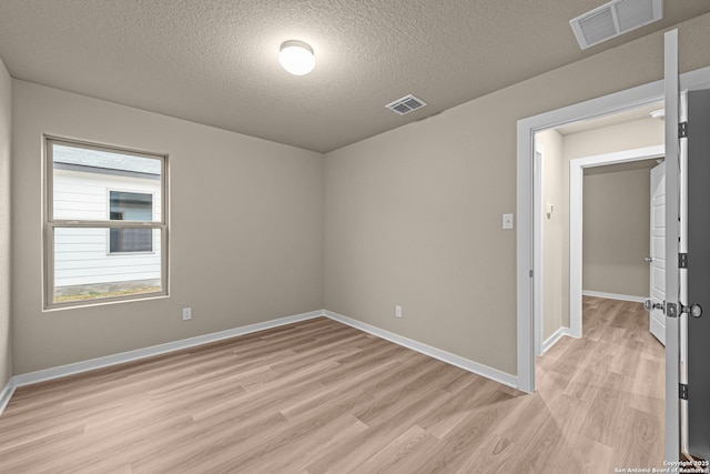 spare room featuring light hardwood / wood-style flooring and a textured ceiling