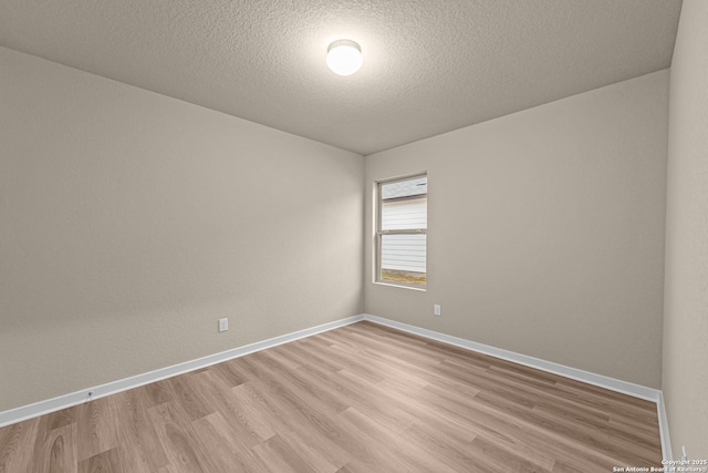 spare room with a textured ceiling and light wood-type flooring