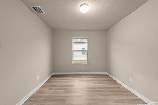 empty room with light hardwood / wood-style floors and a textured ceiling