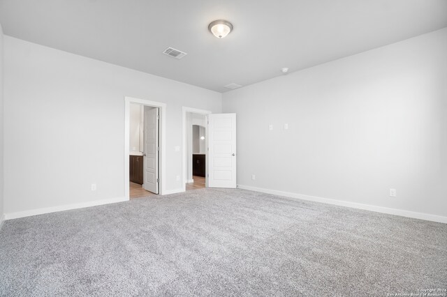 unfurnished bedroom with light colored carpet and ensuite bath