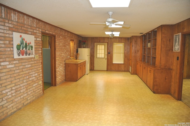 interior space with wood walls, brick wall, a textured ceiling, and ceiling fan