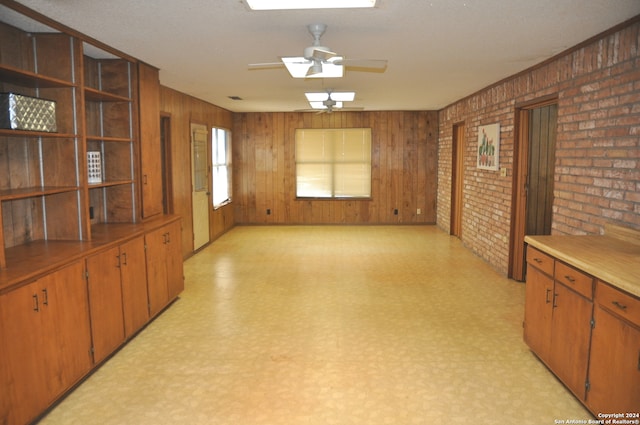 living room featuring wood walls, brick wall, and ceiling fan