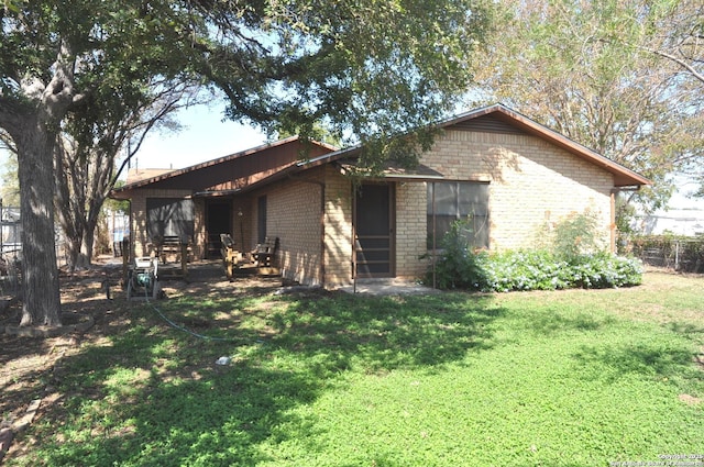 105 S Sayers Dr, Devine, TX 78016 - back of house featuring brick siding and a lawn