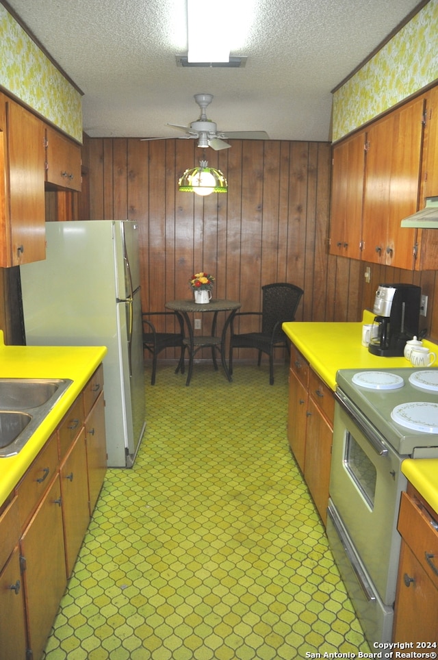 kitchen with wooden walls, ceiling fan, electric stove, and a textured ceiling