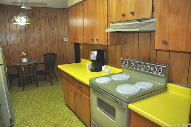 kitchen featuring range with electric stovetop, ceiling fan, wood walls, and refrigerator