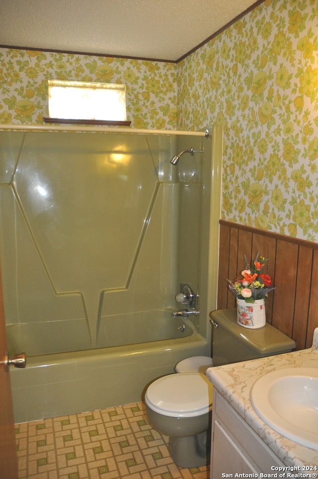 full bathroom featuring wood walls, toilet, shower / bathtub combination, vanity, and a textured ceiling