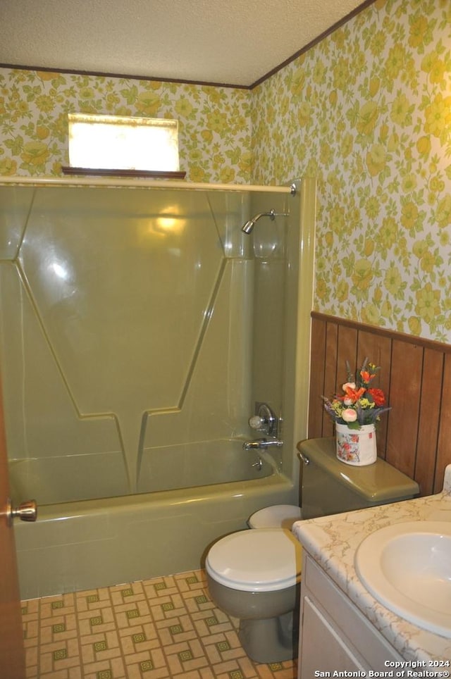 105 S Sayers Dr, Devine, TX 78016 - bathroom with wallpapered walls, wainscoting, a textured ceiling, tub / shower combination, and toilet