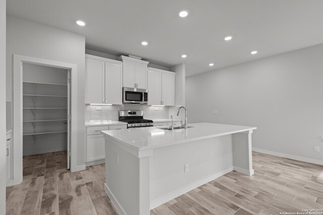 kitchen featuring stainless steel appliances, an island with sink, white cabinets, and sink