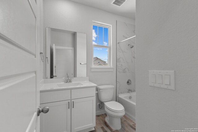 full bathroom with hardwood / wood-style floors, vanity, tiled shower / bath combo, and toilet