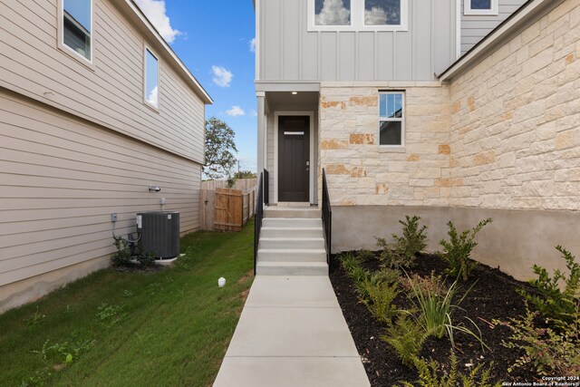 entrance to property featuring central AC and a lawn