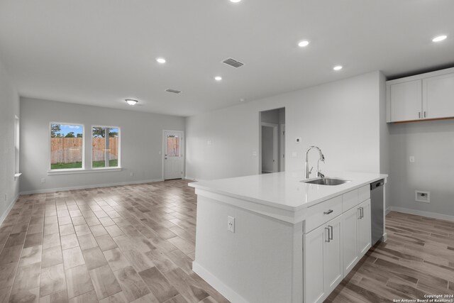 kitchen with an island with sink, sink, stainless steel dishwasher, and white cabinetry