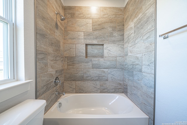 bathroom featuring tiled shower / bath and toilet