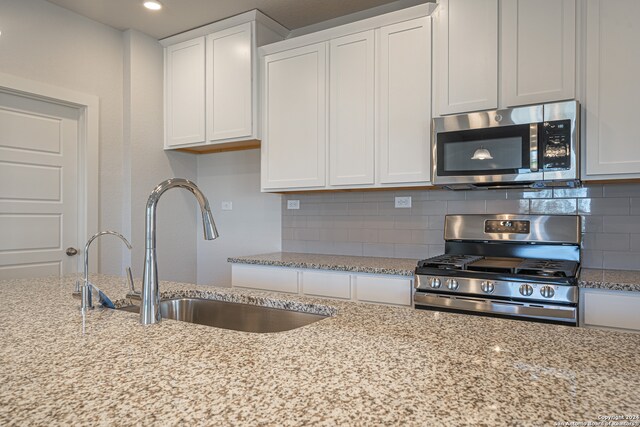 kitchen with stainless steel appliances, sink, decorative backsplash, and white cabinetry