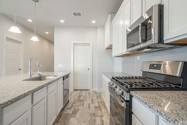 kitchen featuring stainless steel appliances, sink, light stone counters, and white cabinetry