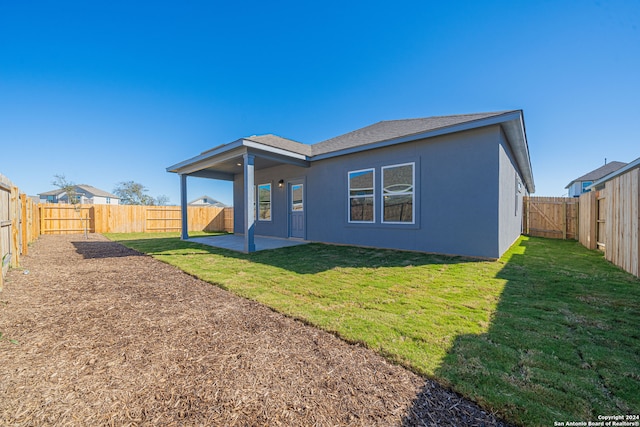 back of house with a patio and a lawn