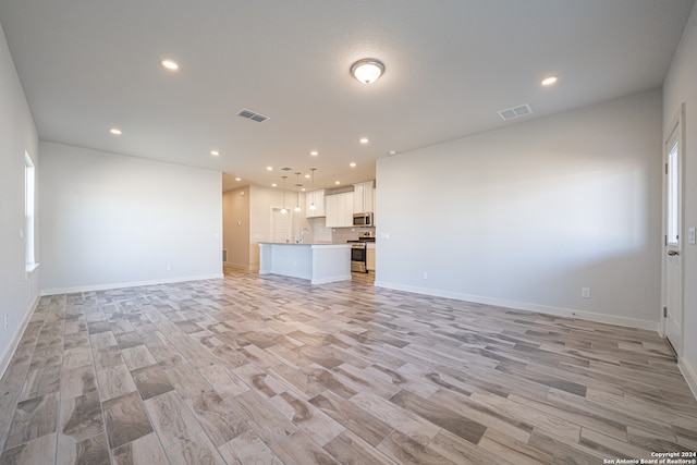 unfurnished living room with sink and light hardwood / wood-style floors