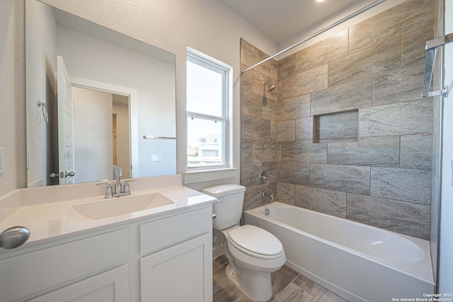 full bathroom featuring tiled shower / bath, vanity, hardwood / wood-style floors, and toilet