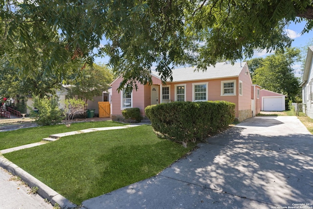 view of front of property featuring a garage, a front lawn, and an outbuilding