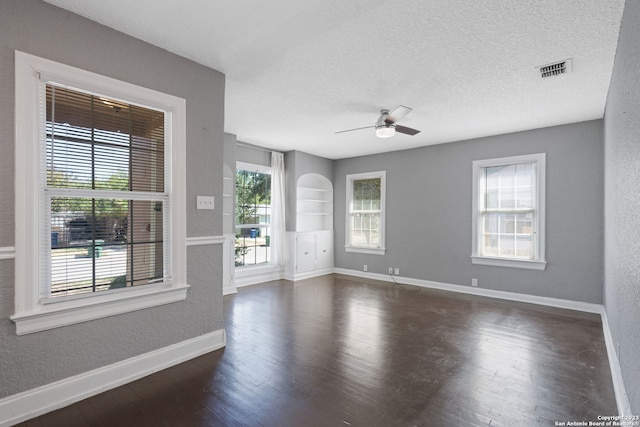 spare room featuring ceiling fan, dark wood-type flooring, and a textured ceiling