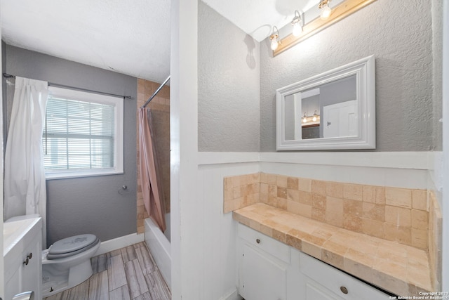 full bathroom featuring vanity, wood-type flooring, a textured ceiling, shower / tub combo, and toilet