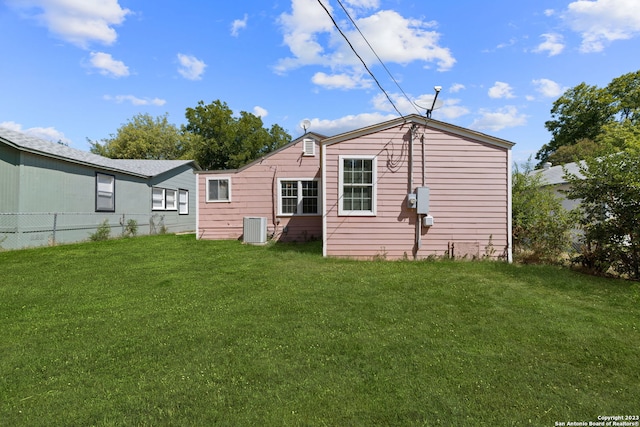 back of property featuring cooling unit and a lawn