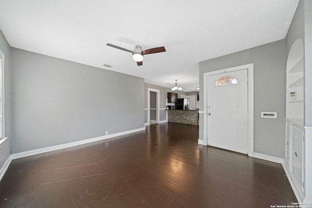 interior space with ceiling fan with notable chandelier and dark hardwood / wood-style floors