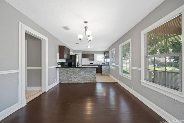 kitchen with dark brown cabinetry, an inviting chandelier, stainless steel fridge, and hardwood / wood-style floors