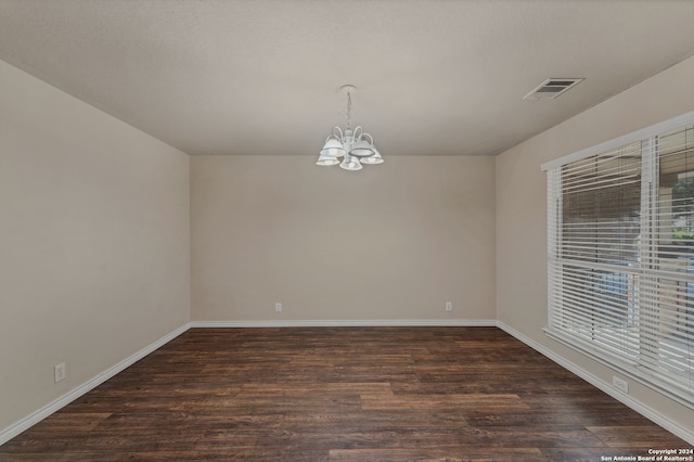 empty room with an inviting chandelier and dark hardwood / wood-style flooring