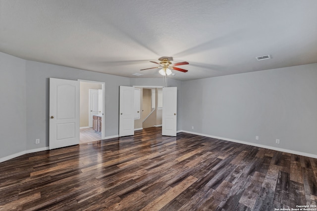 unfurnished bedroom featuring ceiling fan, a textured ceiling, connected bathroom, and dark wood-type flooring