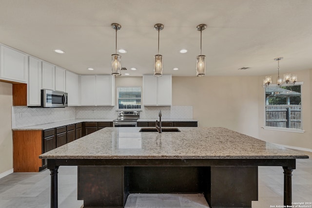 kitchen with decorative light fixtures, sink, stainless steel appliances, light stone countertops, and white cabinetry