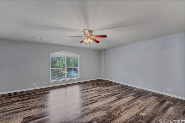 empty room featuring ceiling fan, dark wood-type flooring, and a textured ceiling