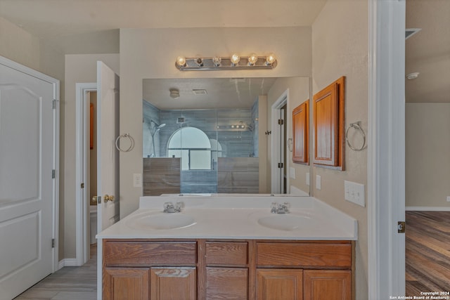 bathroom with walk in shower, vanity, and wood-type flooring