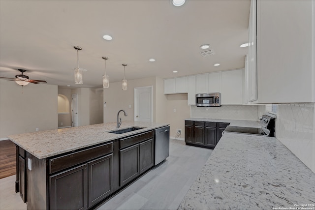 kitchen with sink, light stone countertops, an island with sink, white cabinets, and appliances with stainless steel finishes