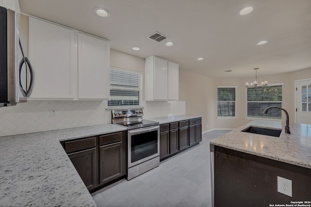 kitchen with dark brown cabinetry, sink, light stone countertops, white cabinets, and appliances with stainless steel finishes