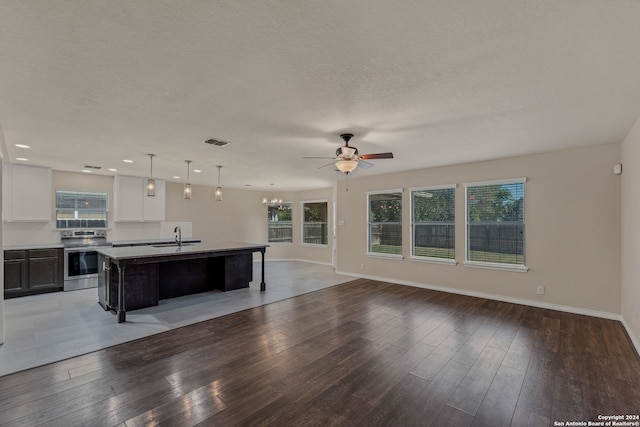 kitchen with sink, stainless steel range with electric stovetop, a kitchen island with sink, dark wood-type flooring, and white cabinetry