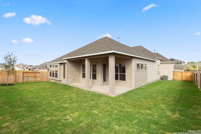 rear view of property with a lawn, a patio area, and central AC unit