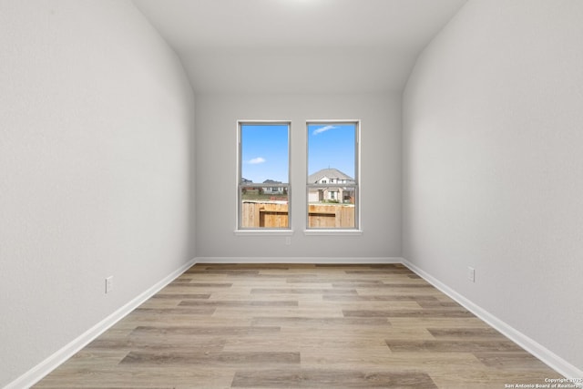 spare room featuring light hardwood / wood-style floors and lofted ceiling