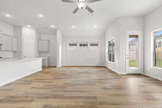 unfurnished living room featuring ceiling fan, sink, and light hardwood / wood-style floors