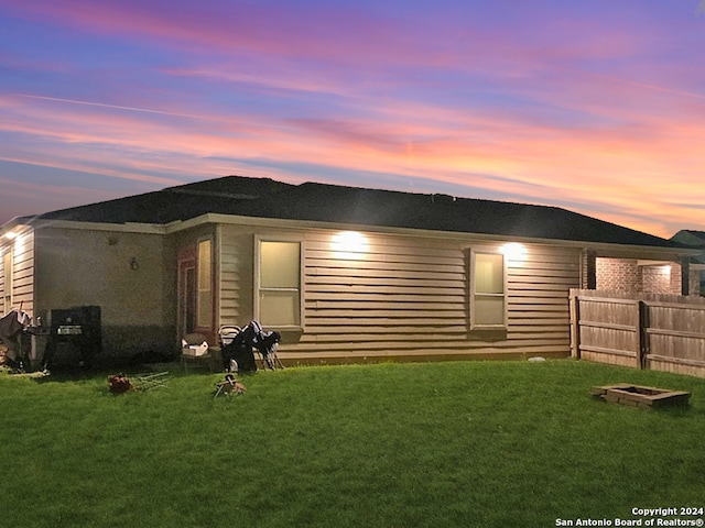 back house at dusk with a lawn