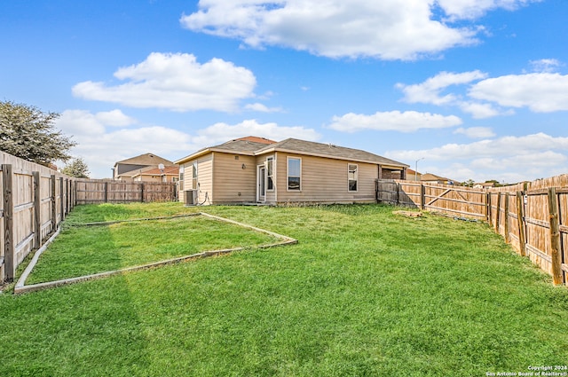 back of property with central AC and a lawn