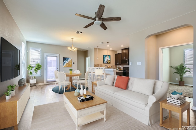 living room featuring ceiling fan with notable chandelier and light wood-type flooring