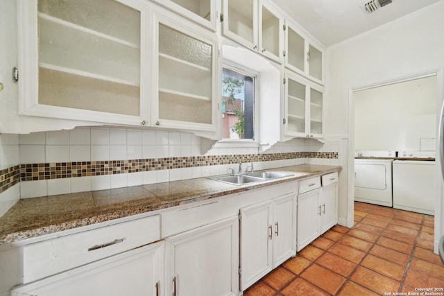 kitchen featuring decorative backsplash, sink, washer and dryer, light tile patterned floors, and white cabinetry