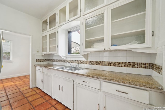 kitchen with decorative backsplash, white cabinetry, sink, and light tile patterned floors