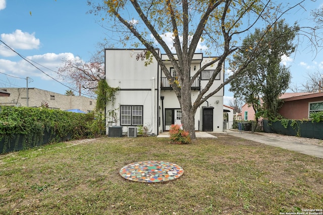 back of property featuring a yard, a balcony, and central AC unit