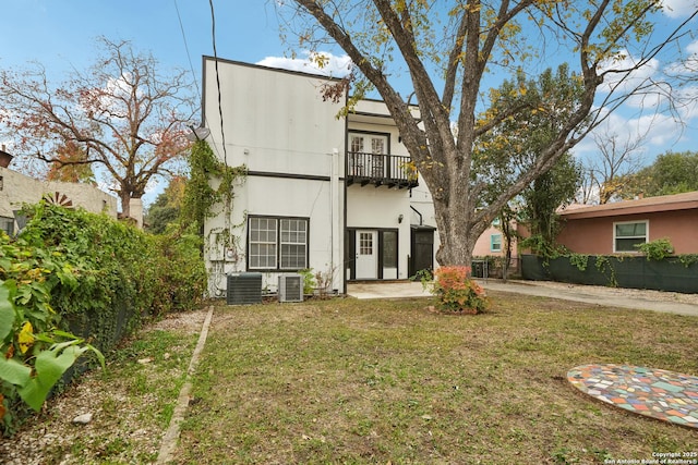 rear view of house featuring a yard, central air condition unit, and a balcony