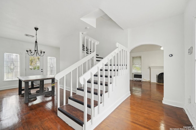 stairs with hardwood / wood-style floors and an inviting chandelier